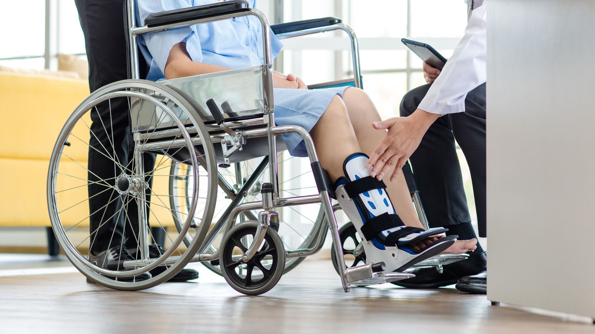 Person in wheelchair being assisted by another person in a bright indoor setting