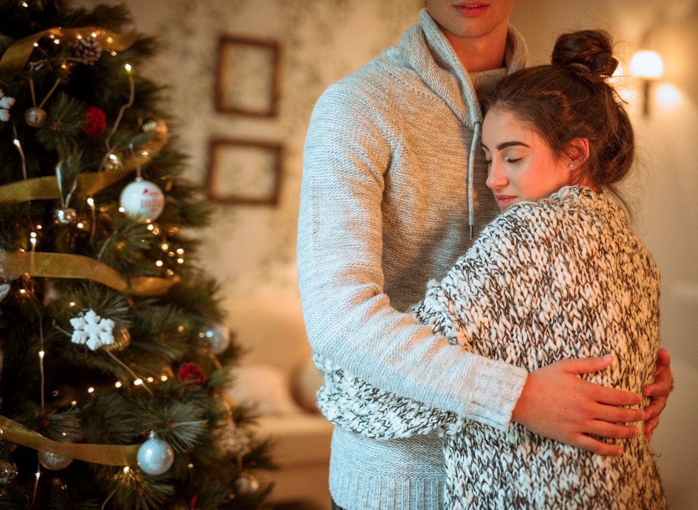 Couple embracing beside a decorated Christmas tree in a cozy room