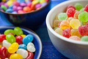 Three bowls filled with colorful assorted candies, including jelly beans, gumdrops, and chocolate-coated candies.