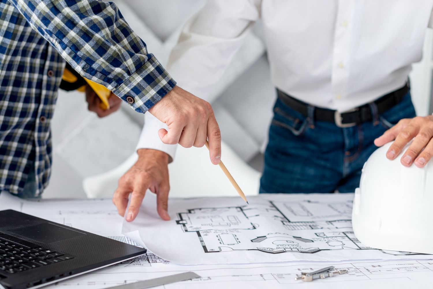 Two men are looking at a blueprint on a table.