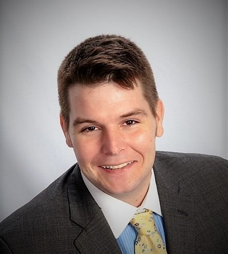 A man in a suit and tie is smiling for the camera.