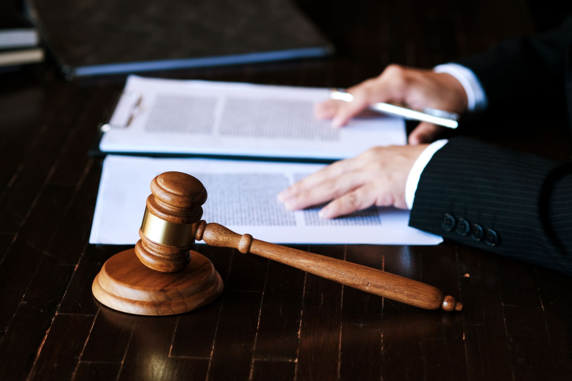 A man in a suit is sitting at a table with papers and a judge 's gavel.
