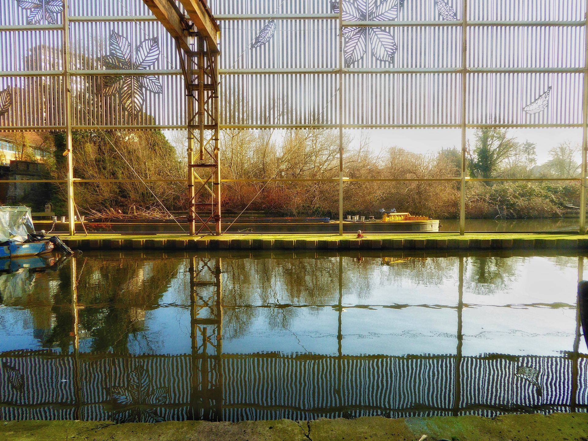 A fence surrounds a body of water with trees in the background