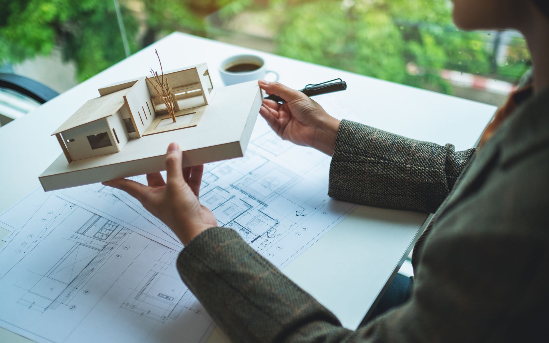 A woman is sitting at a table holding a model of a house.