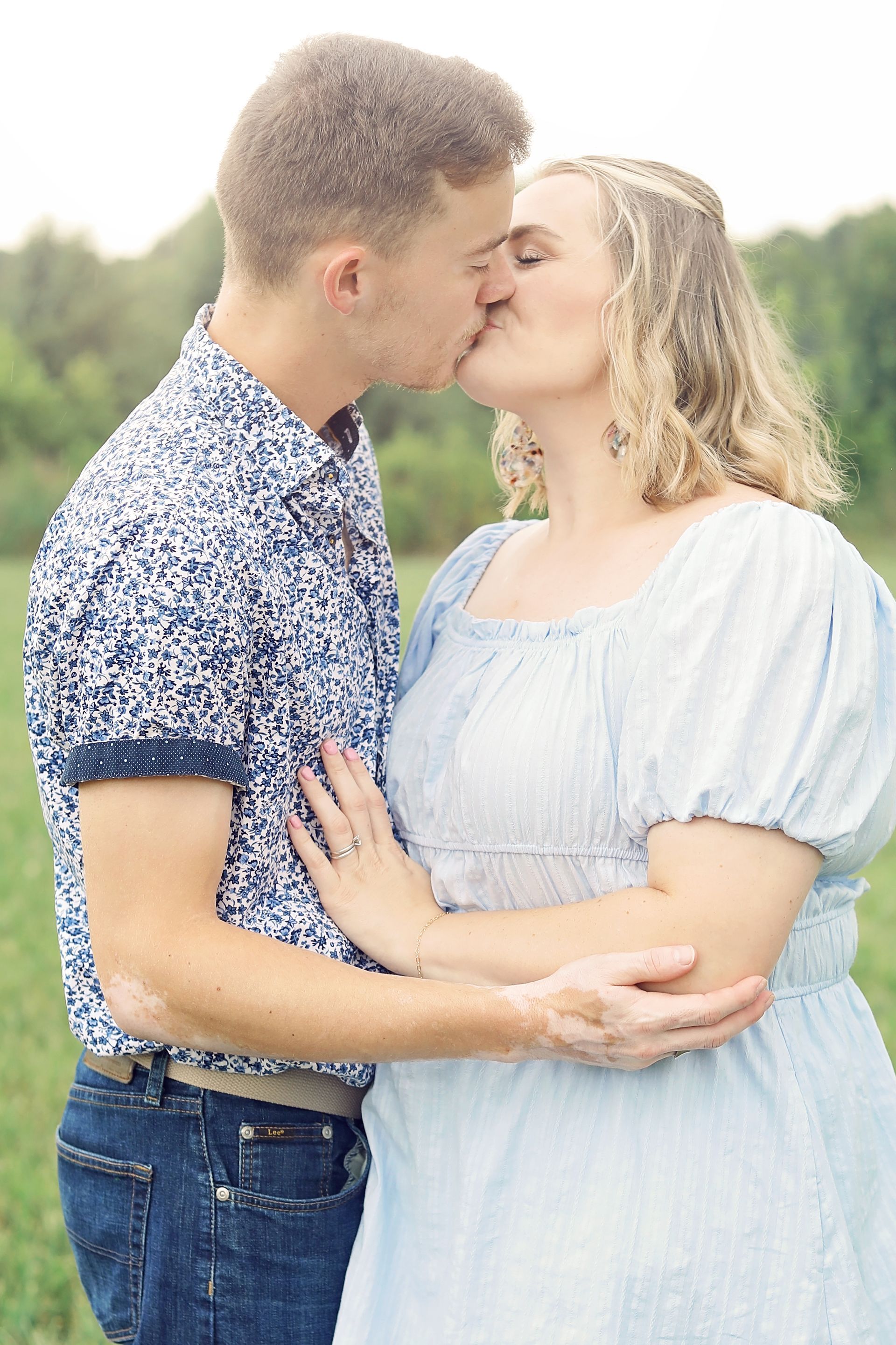 A man and a woman are kissing in a field.