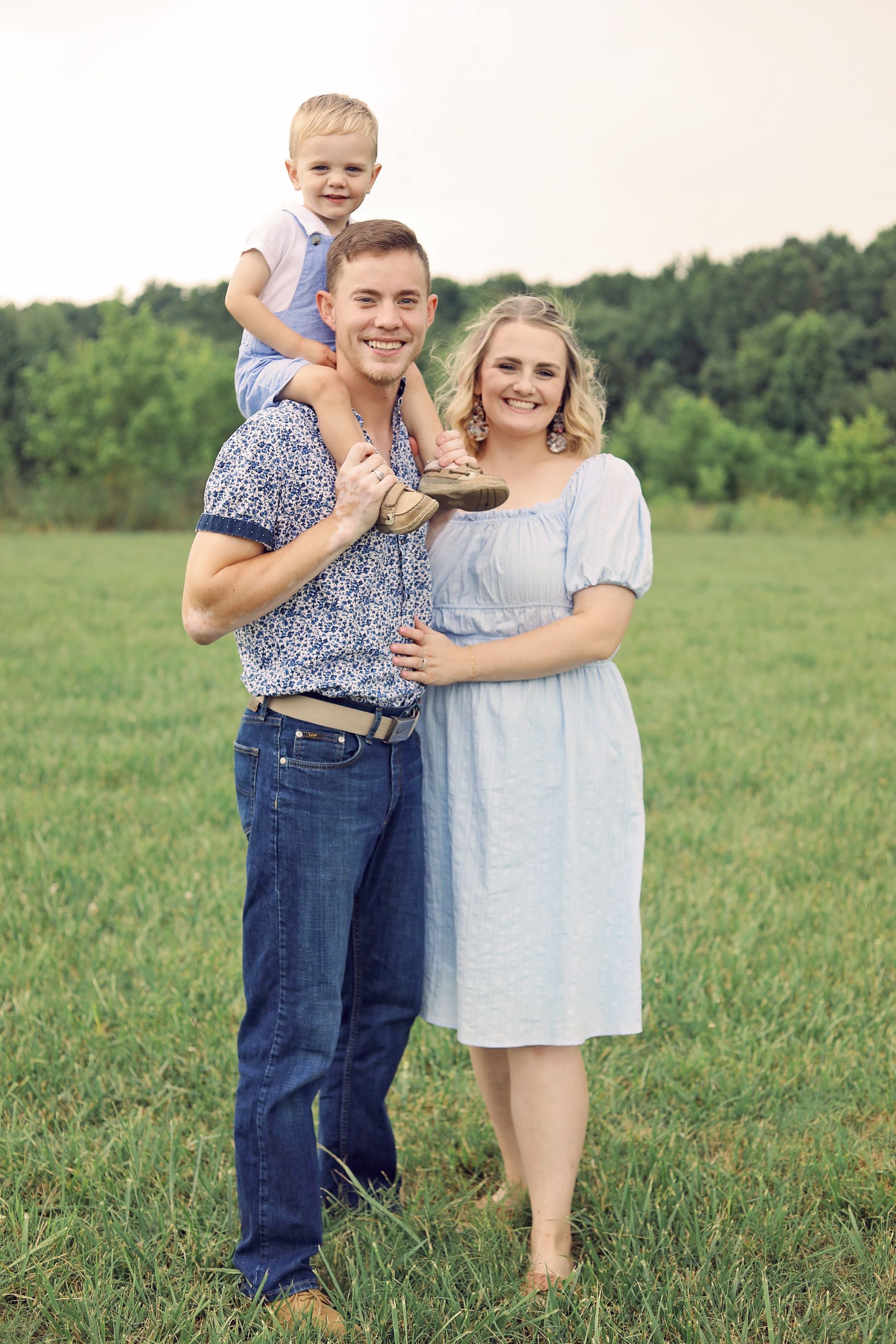 A man is holding a child on his shoulders in a field.