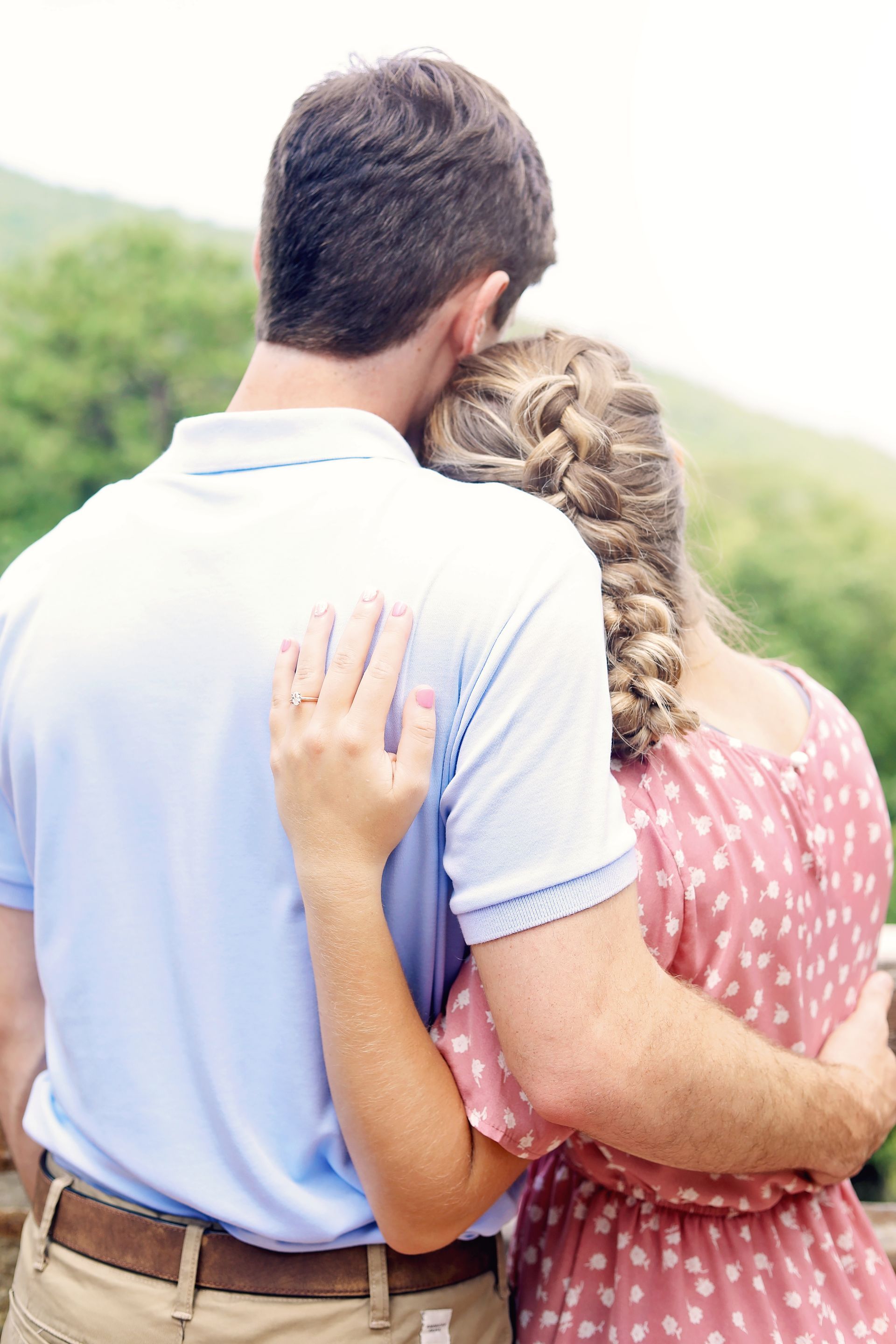 A man and a woman are hugging each other and looking at the mountains.