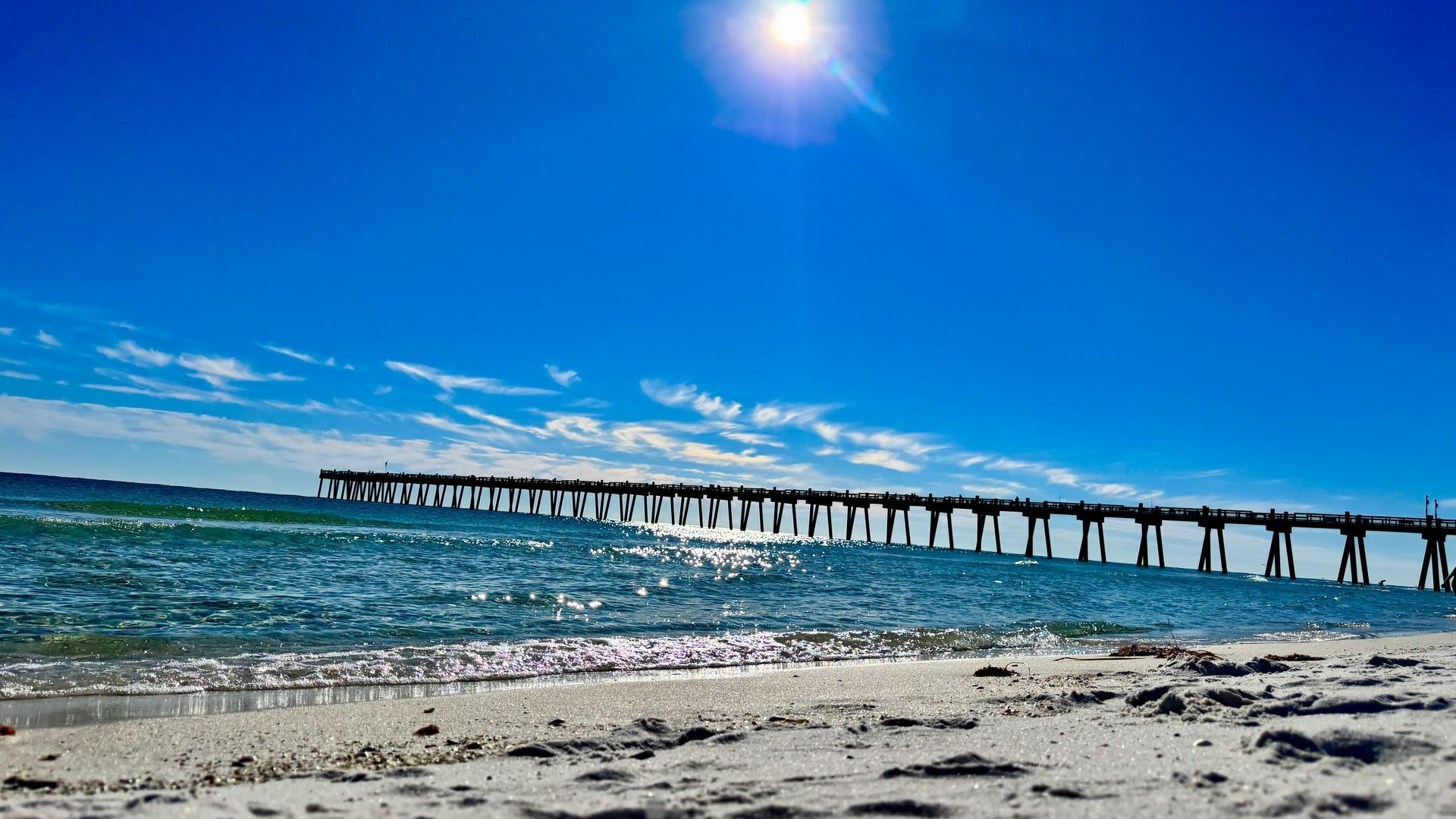 A pier leading into the ocean on a sunny day.