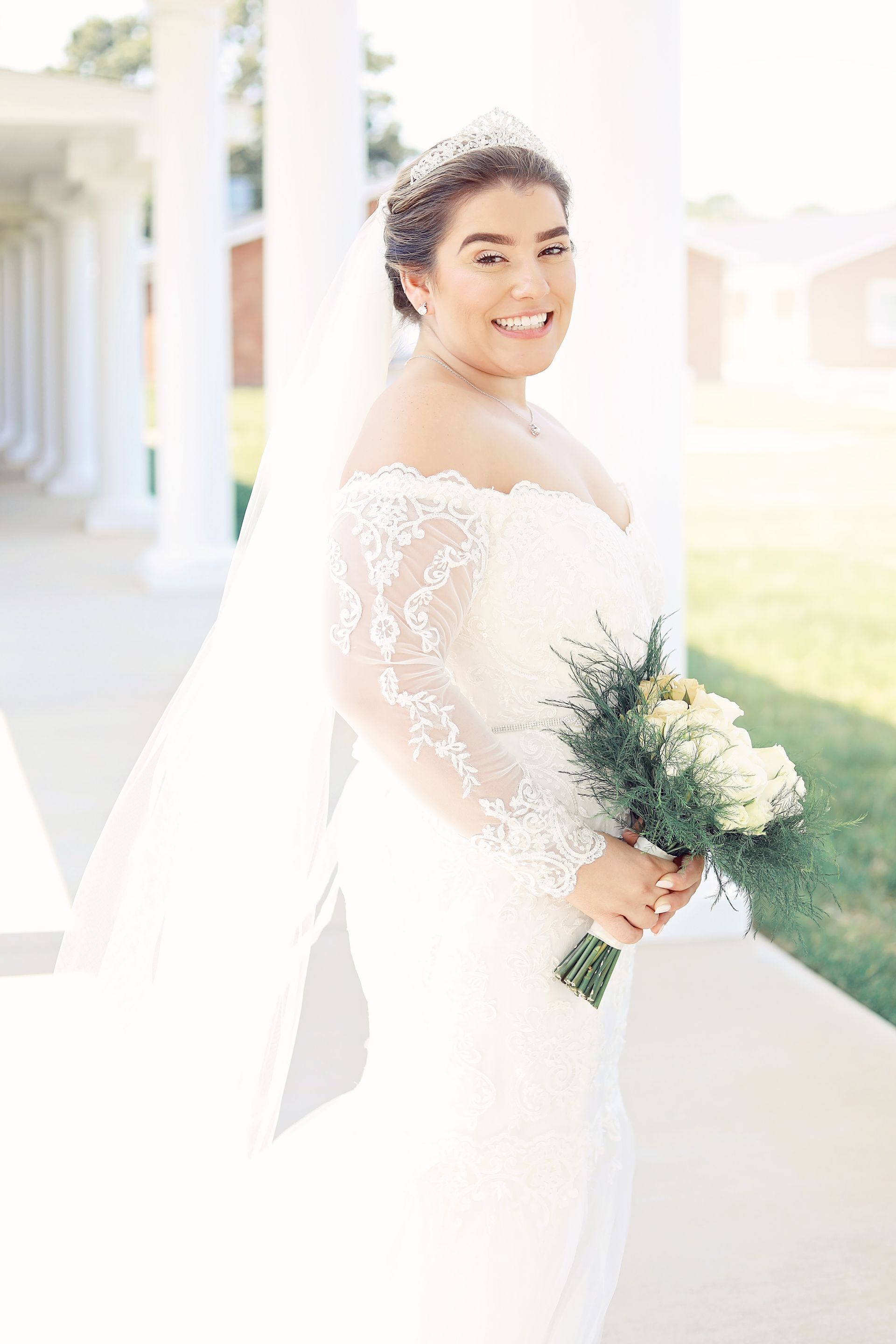 The bride is wearing a veil and holding a bouquet of flowers.