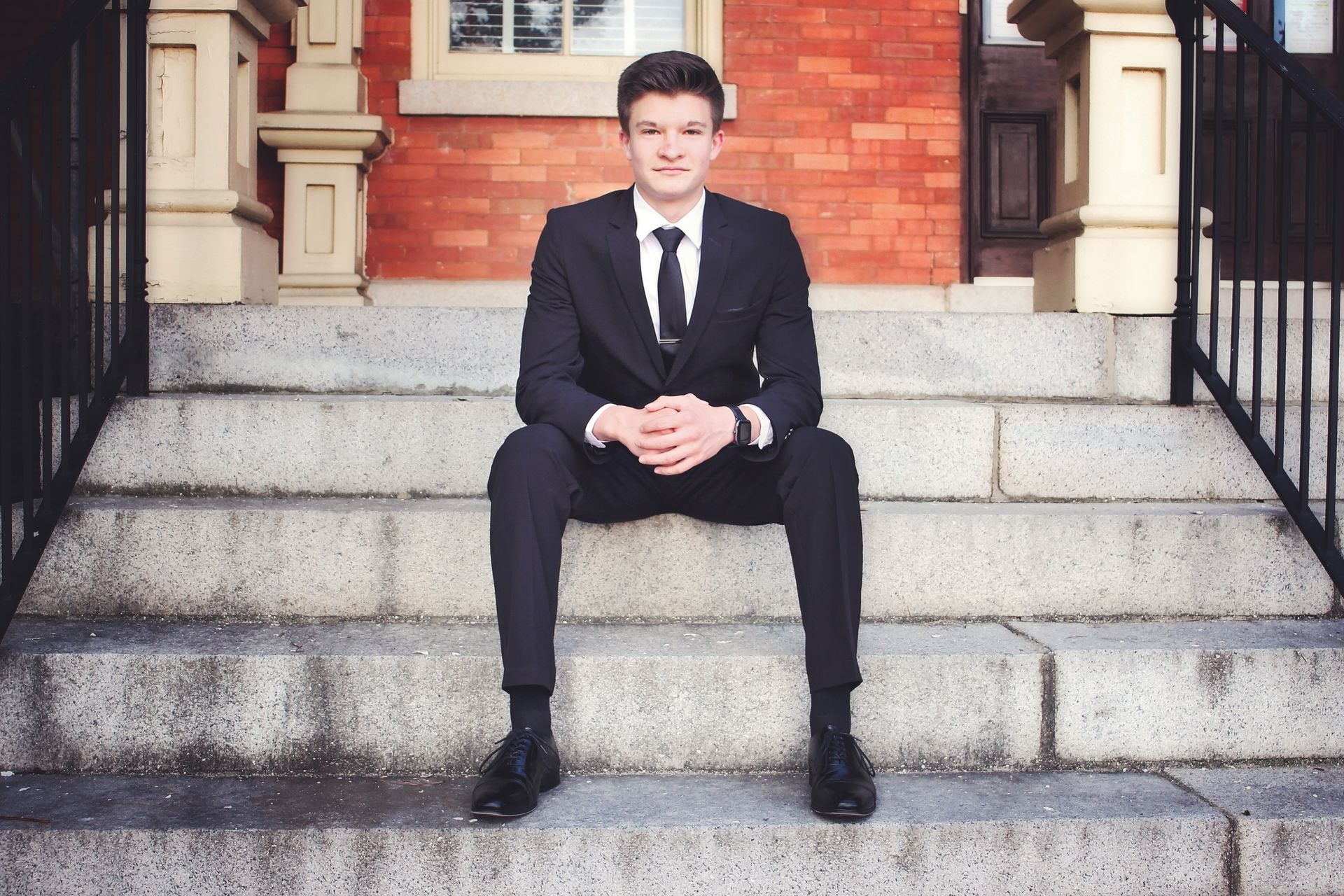 A man in a suit and tie is sitting on the steps of a building
