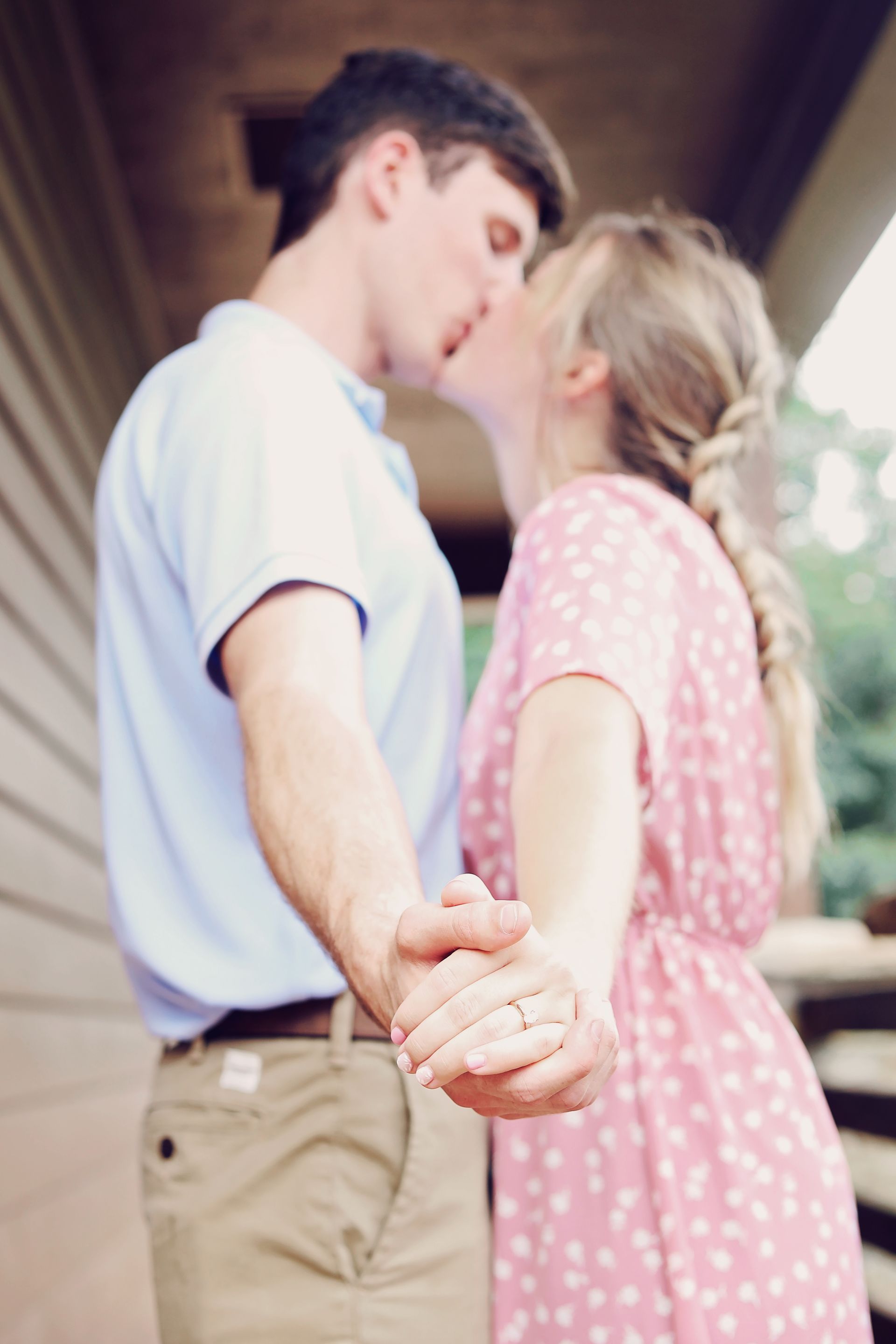 A man and a woman are kissing while holding hands.