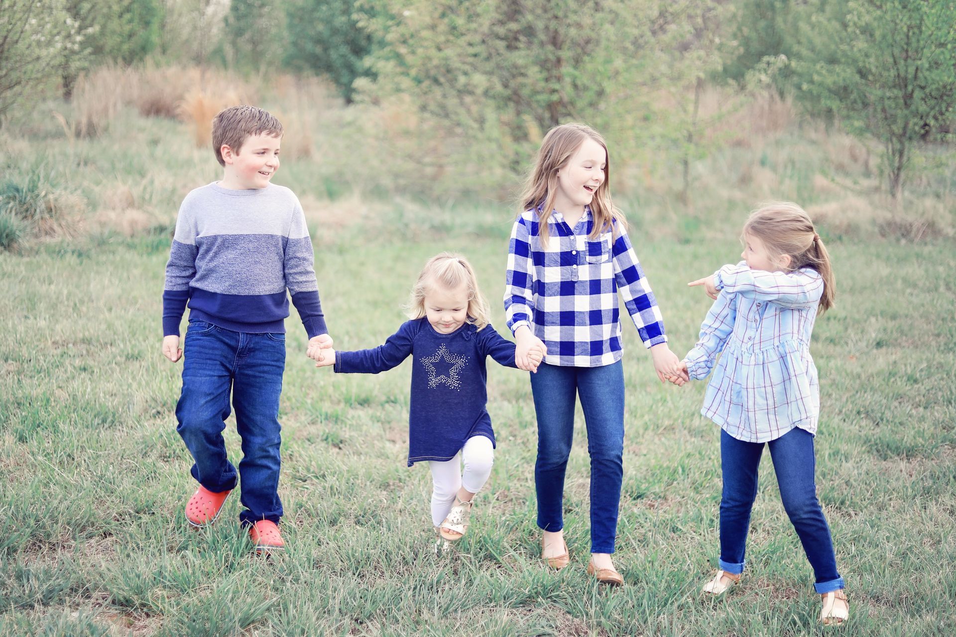 A group of children are holding hands and walking in a field.
