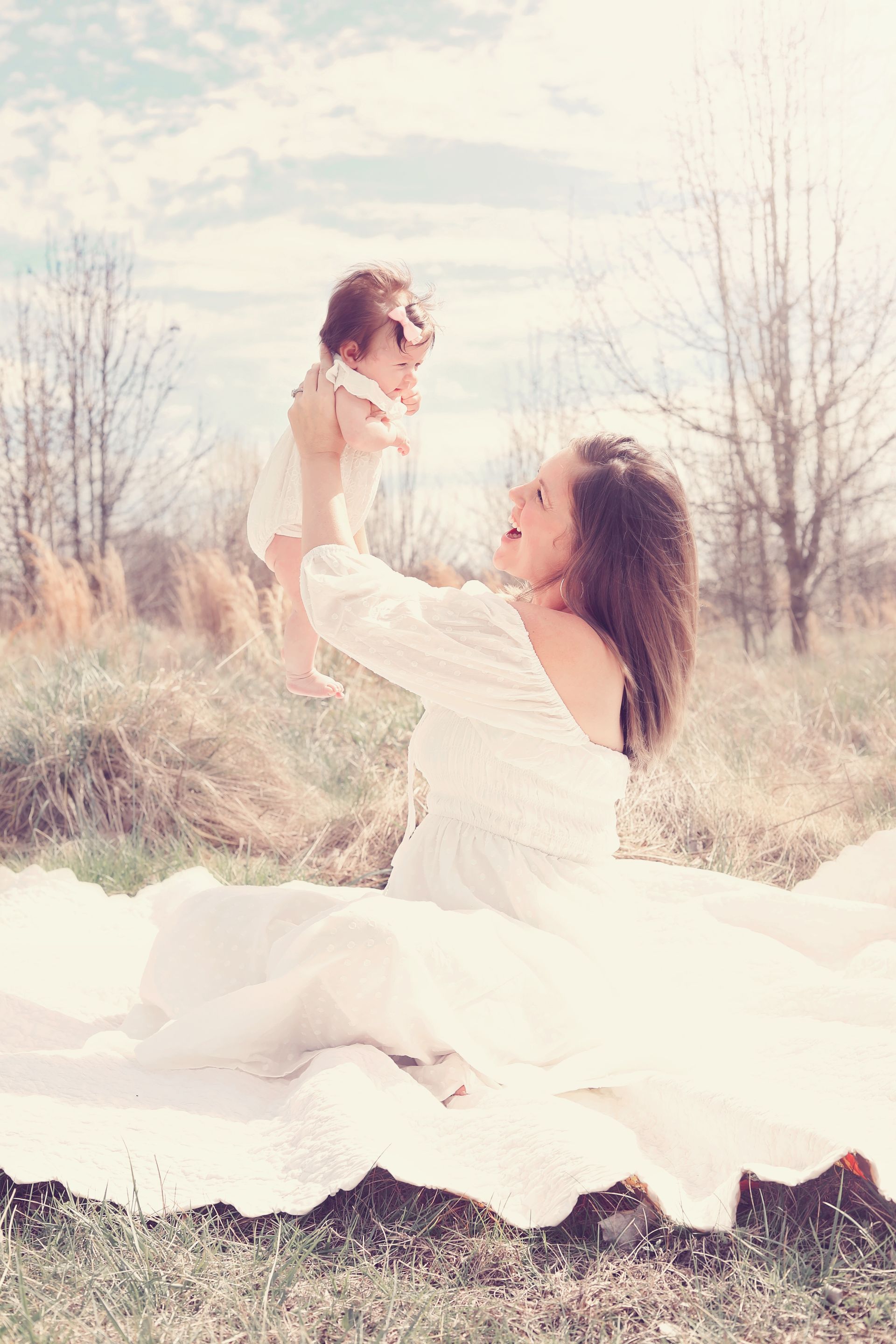 A woman in a white dress is holding a baby in her arms.