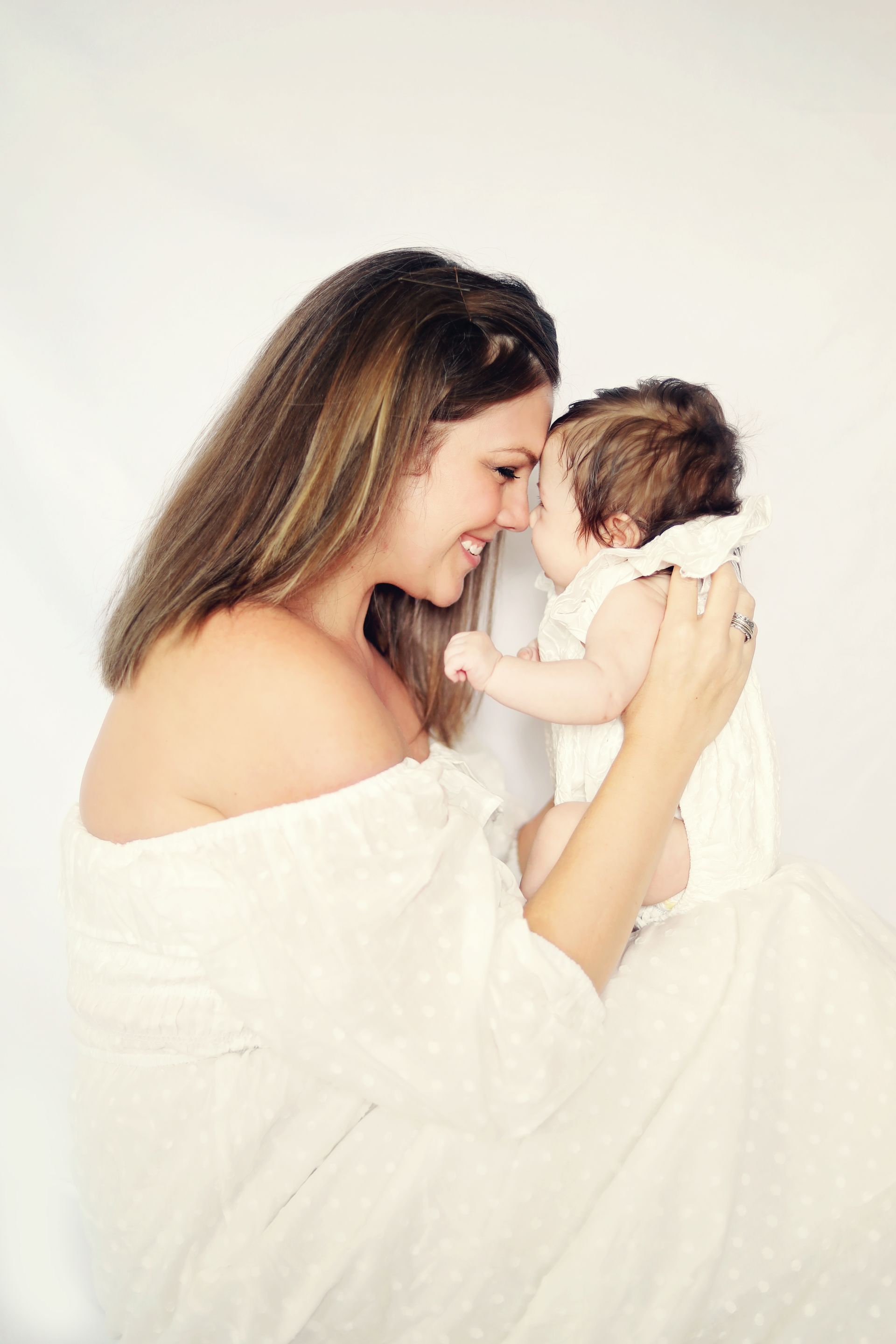 A woman is holding a baby in her arms and the baby is looking at the camera.
