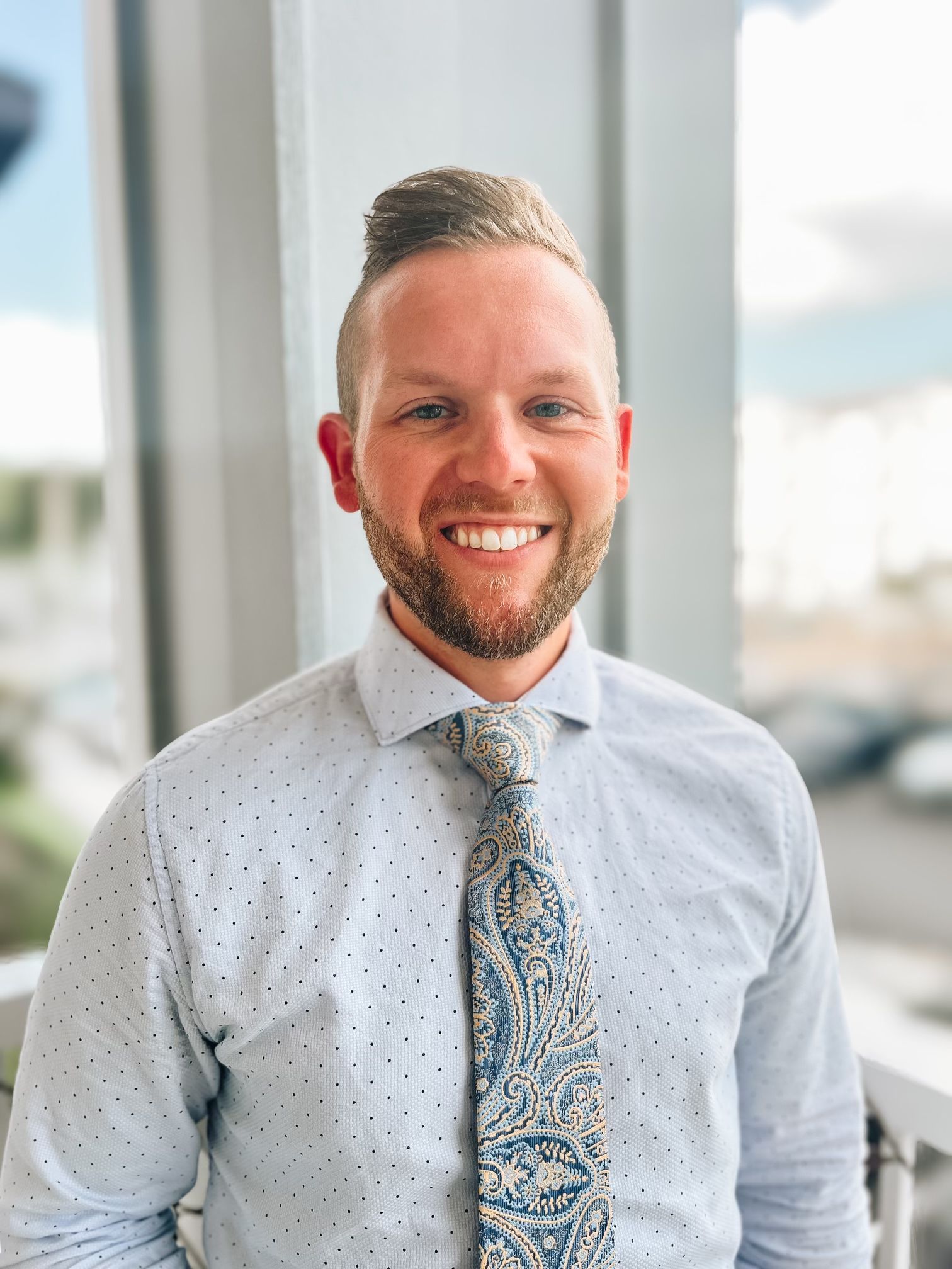 A man in a white shirt and tie is smiling for the camera.