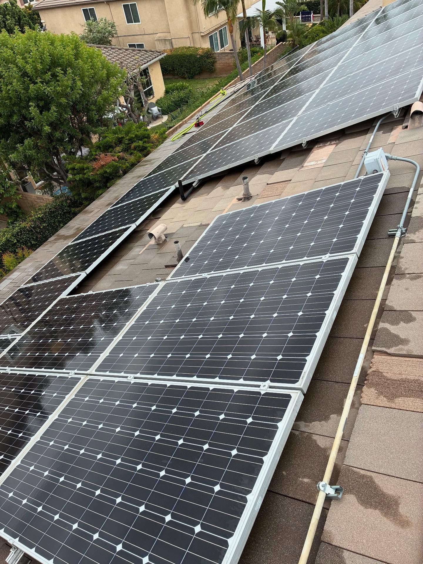 Solar panels installed on a rooftop, angled towards the sky. The dark panels are on a brown roof, likely absorbing sunlight for energy.