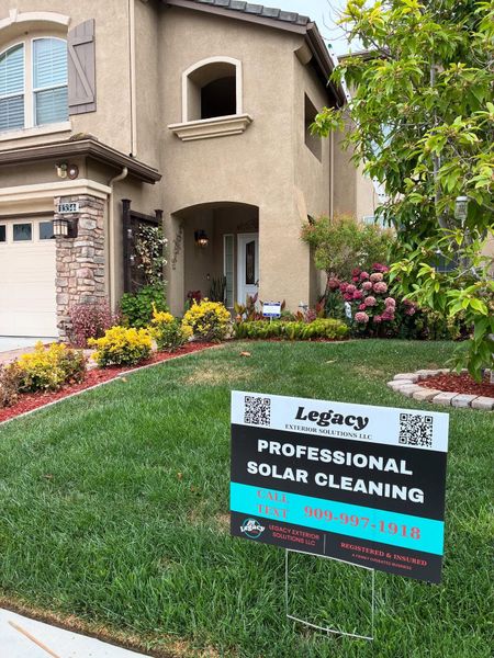 Sign in front of a two-story house advertising professional solar cleaning.