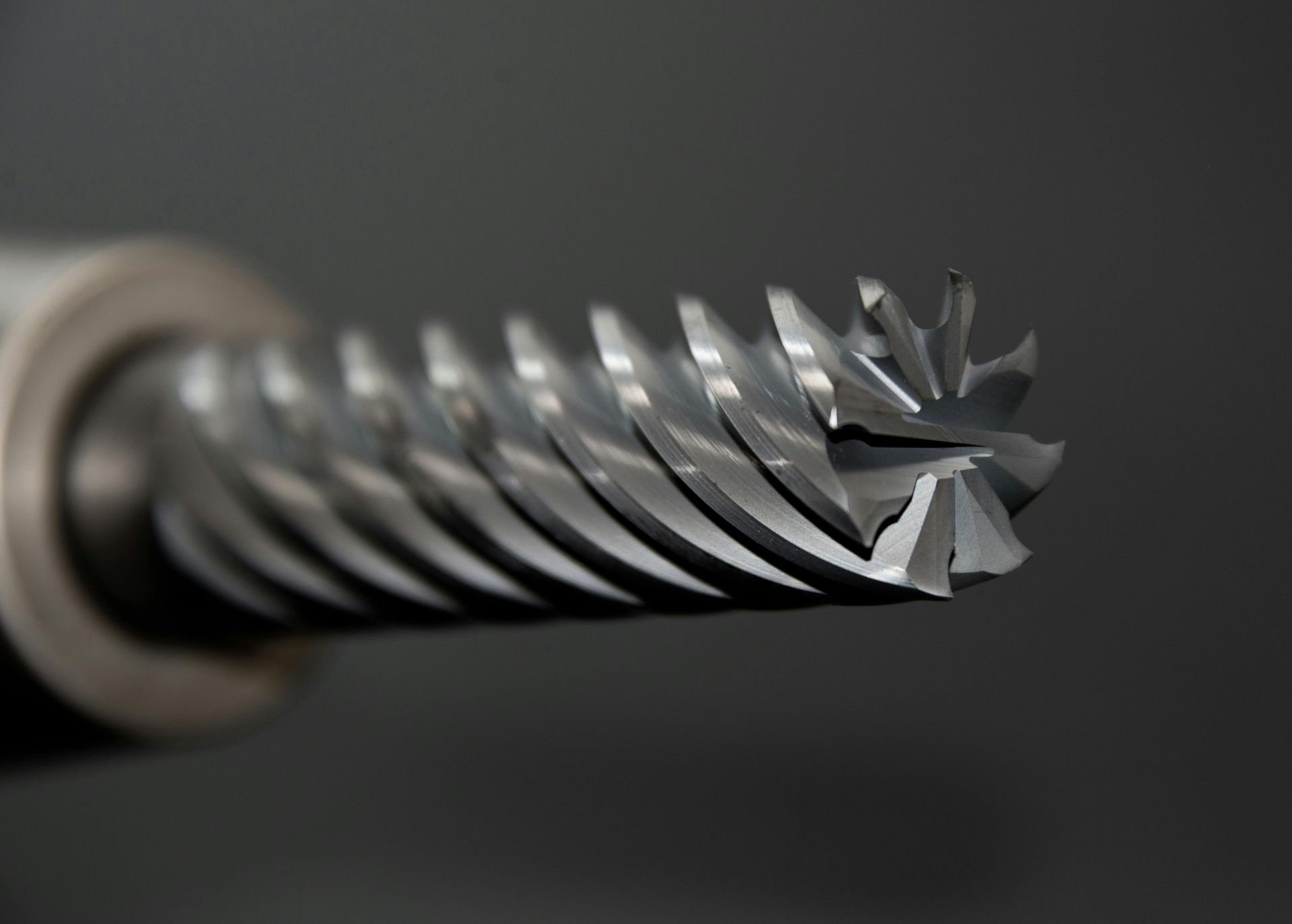 Close-up of a spiral-fluted rotary cutting tool for machining, with sharp edges and a silver finish.