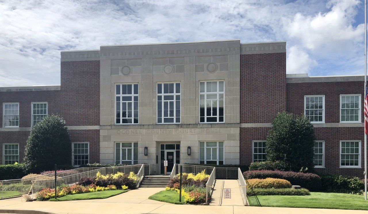 Brick and stone building with symmetrical windows and landscaping; sunny day.