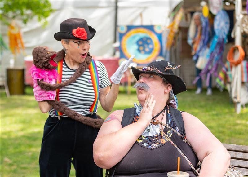 Woman at pottery wheel; another assists with a sponge, outdoors.