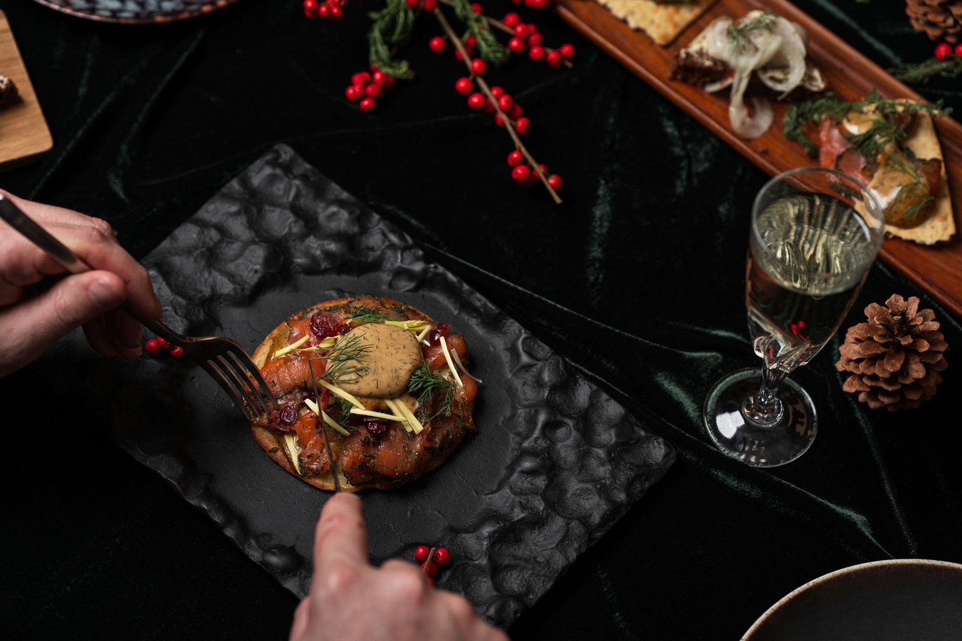 Mynd ofan af hátíðarveislu á dökku borði, með ýmsum réttum, kertum og vínglösum.