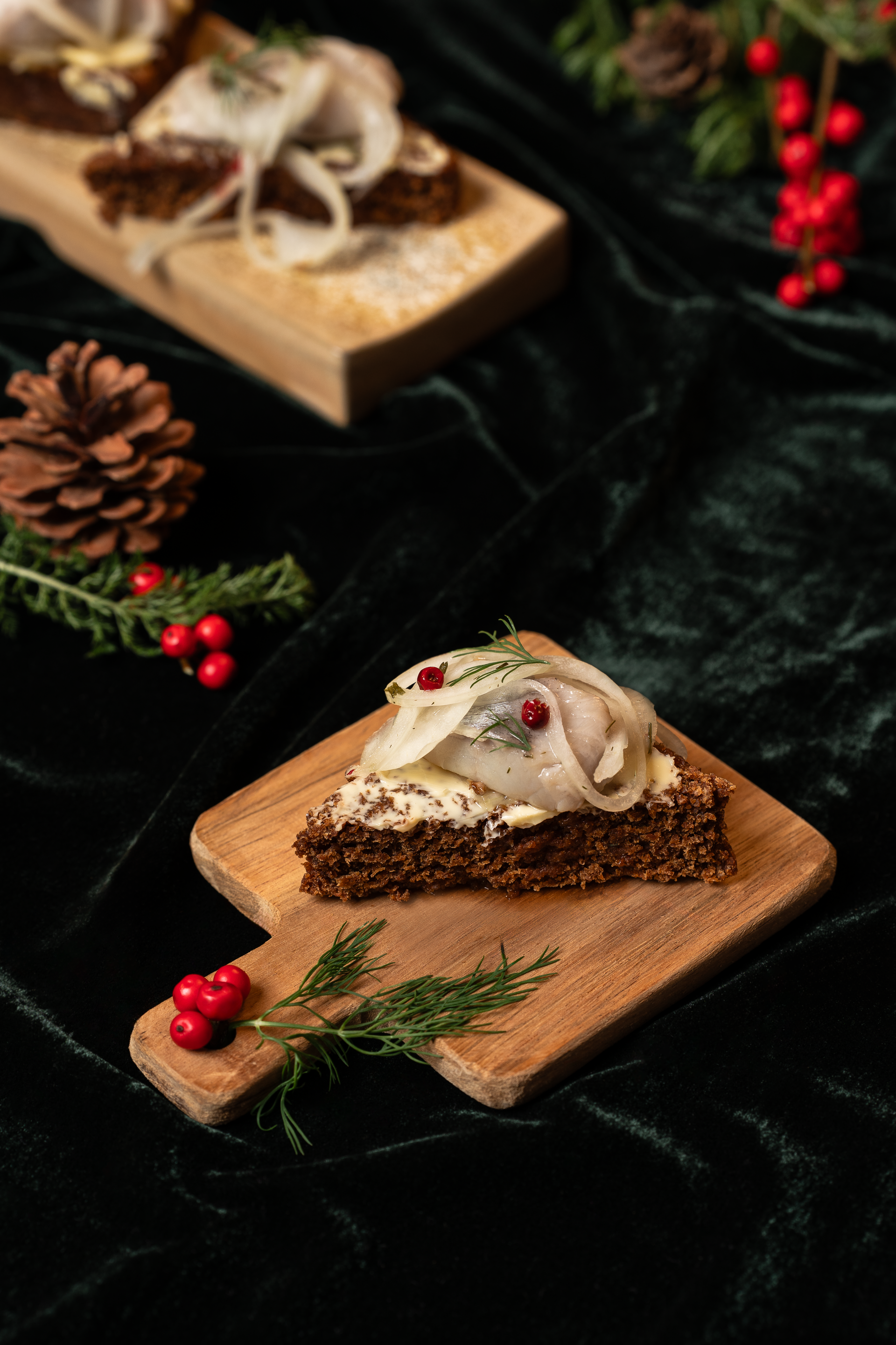 Opin samloka með síld og lauk á dökku brauði, borin fram á trébretti; hátíðarskreytingar í bakgrunni.