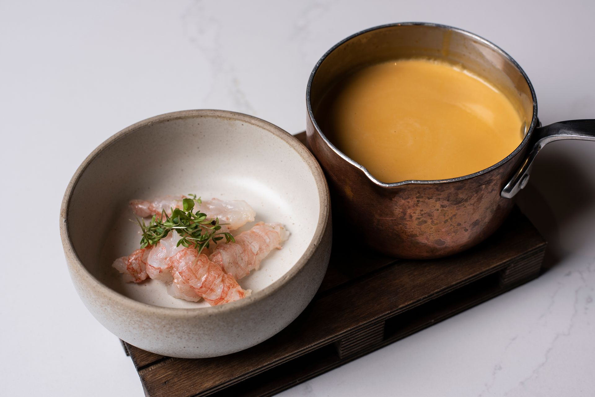 Skál af rækjum og pottur af appelsínusósu á trébakka.