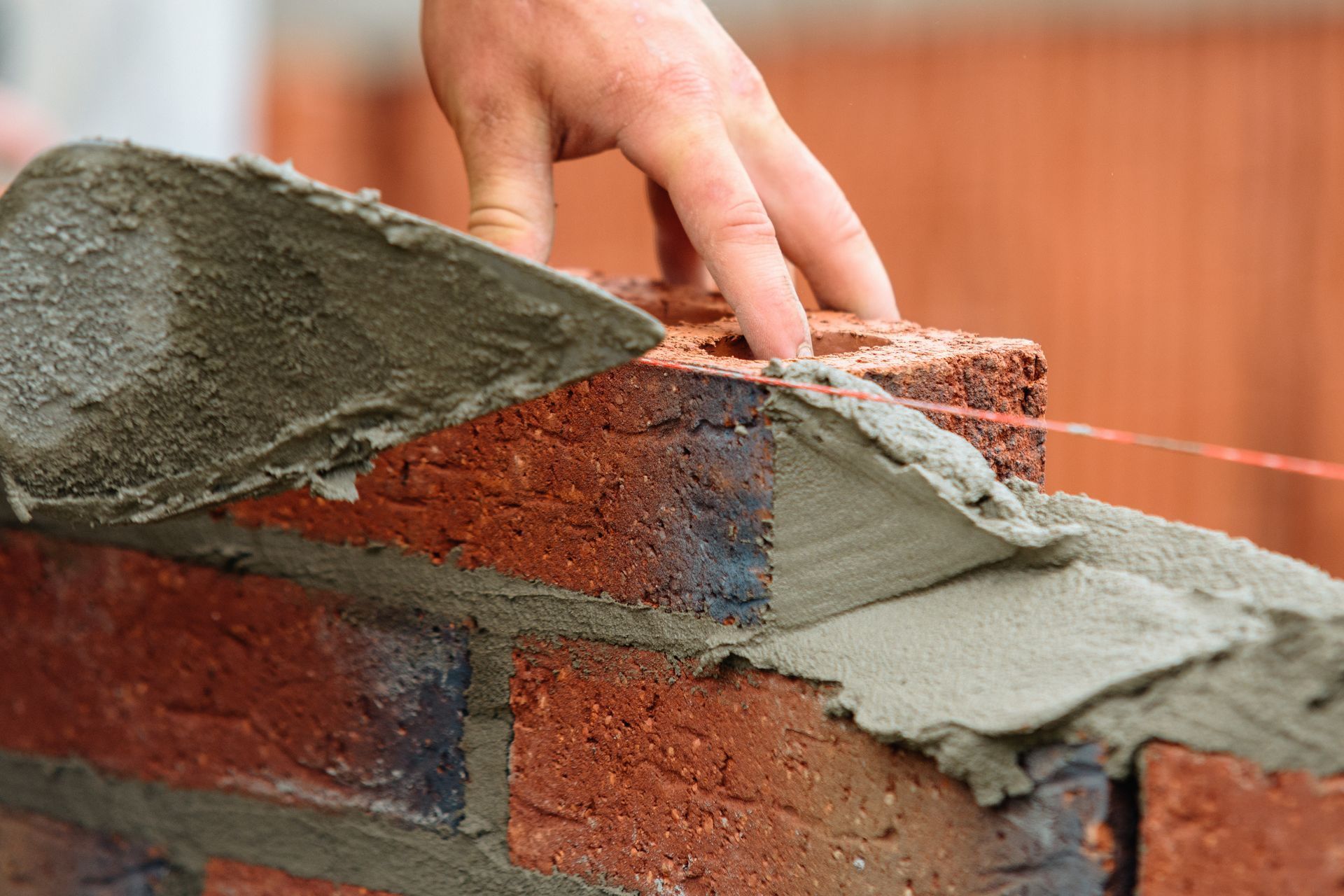 Mason spreading mortar on a brick wall with a trowel