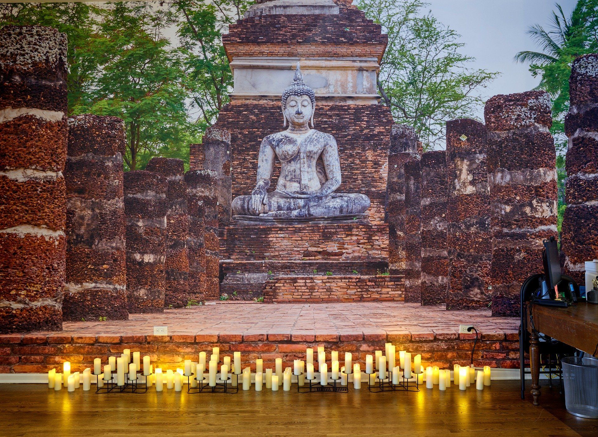 mural of Buddha in the Metaphysical pilates studio surronded by lit candkes