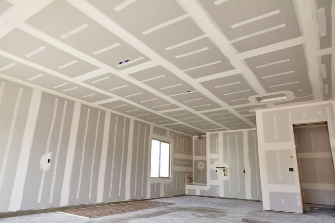 Unfinished room with drywall seams, white walls, a window, and a doorway under construction Unfinished room with drywall seams, white walls, a window, and a doorway under construction