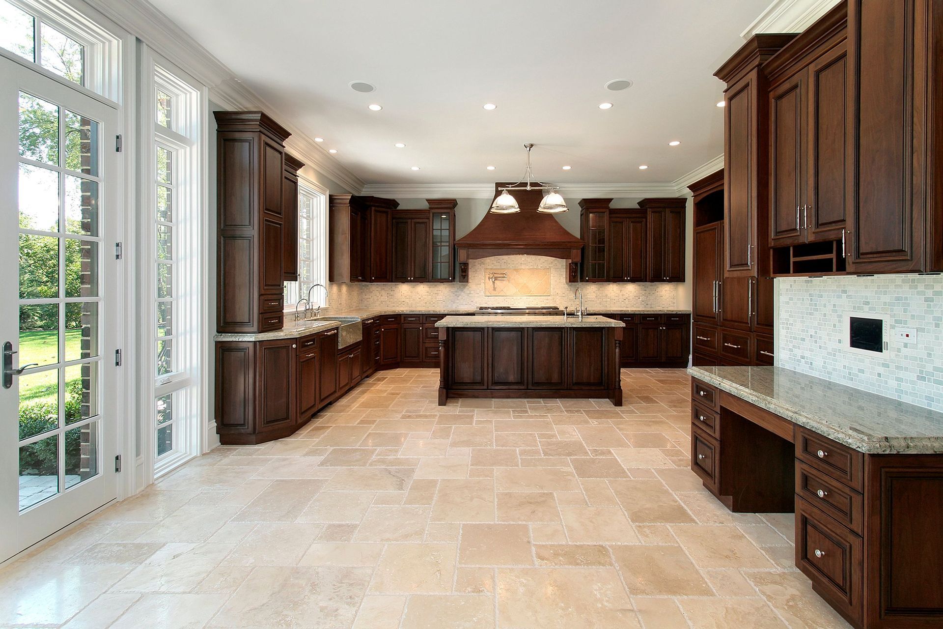 Spacious modern kitchen with dark wood cabinets, beige tile floor, central island, and large windows.