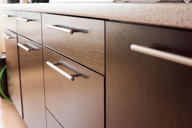Modern kitchen cabinets with silver handles and a dark wood finish, viewed close up Modern kitchen cabinets with silver handles and a dark wood finish, viewed close up