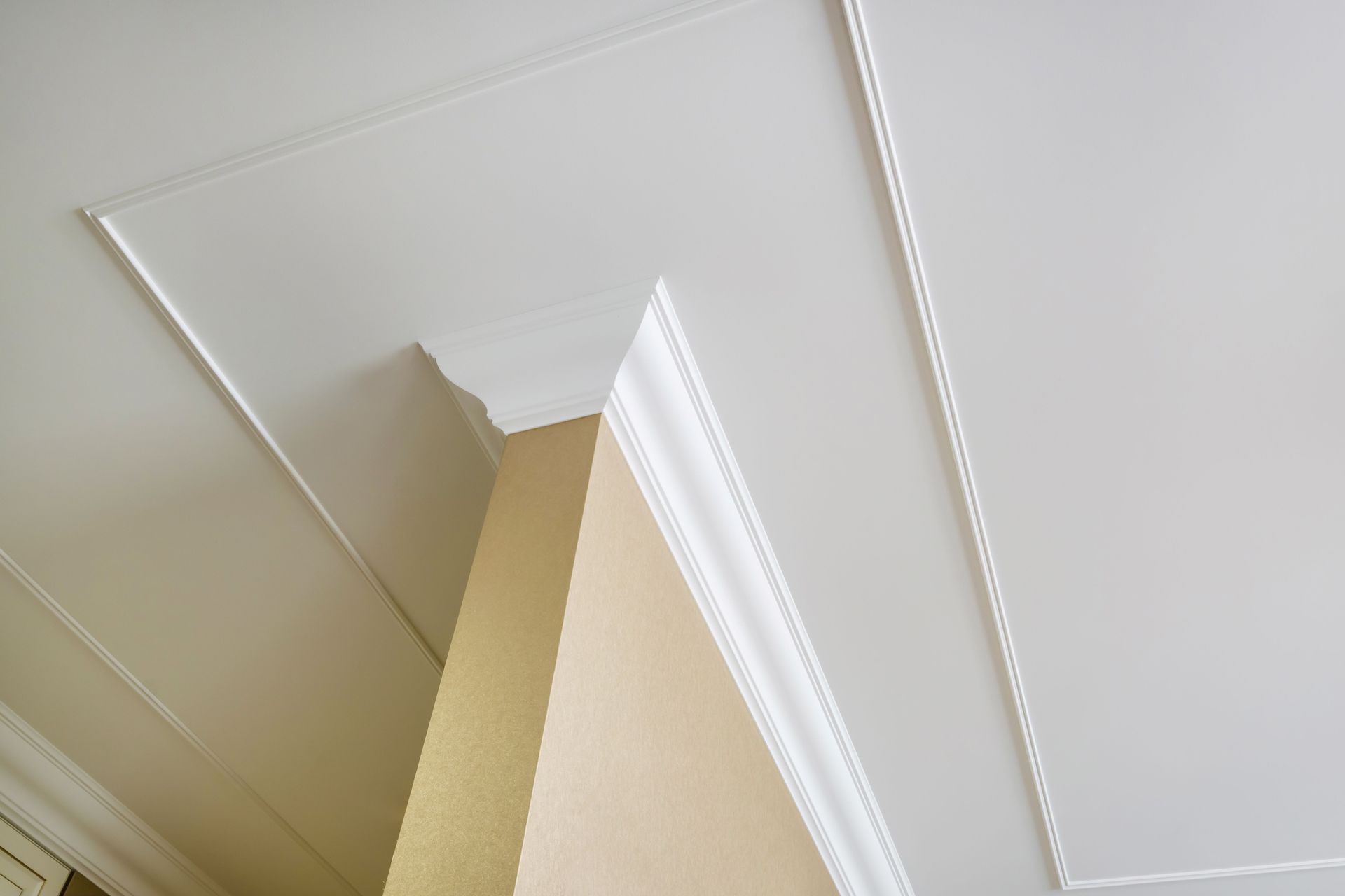 Ceiling corner with white crown molding and beige wall/ceiling intersection