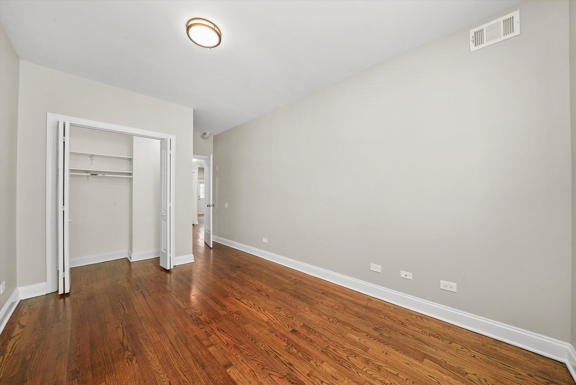 Empty room with hardwood floors, closet, and light fixtures.