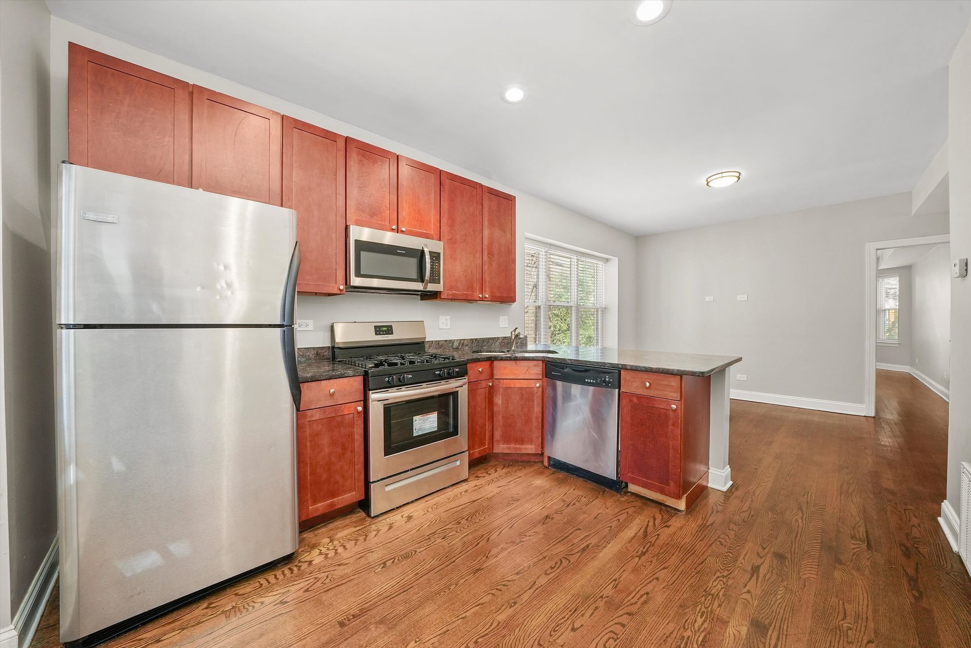 Kitchen with stainless steel appliances, dark wood cabinets, and hardwood floors.