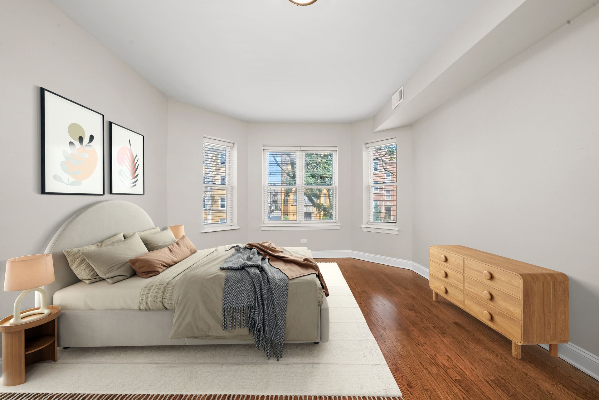 Bedroom with a bed, dresser, and windows. Hardwood floors and neutral tones.