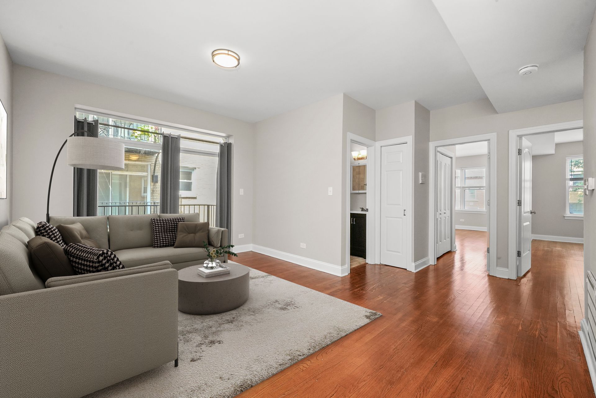 Living room with gray sofa, rug, and coffee table. Dark wood floors.