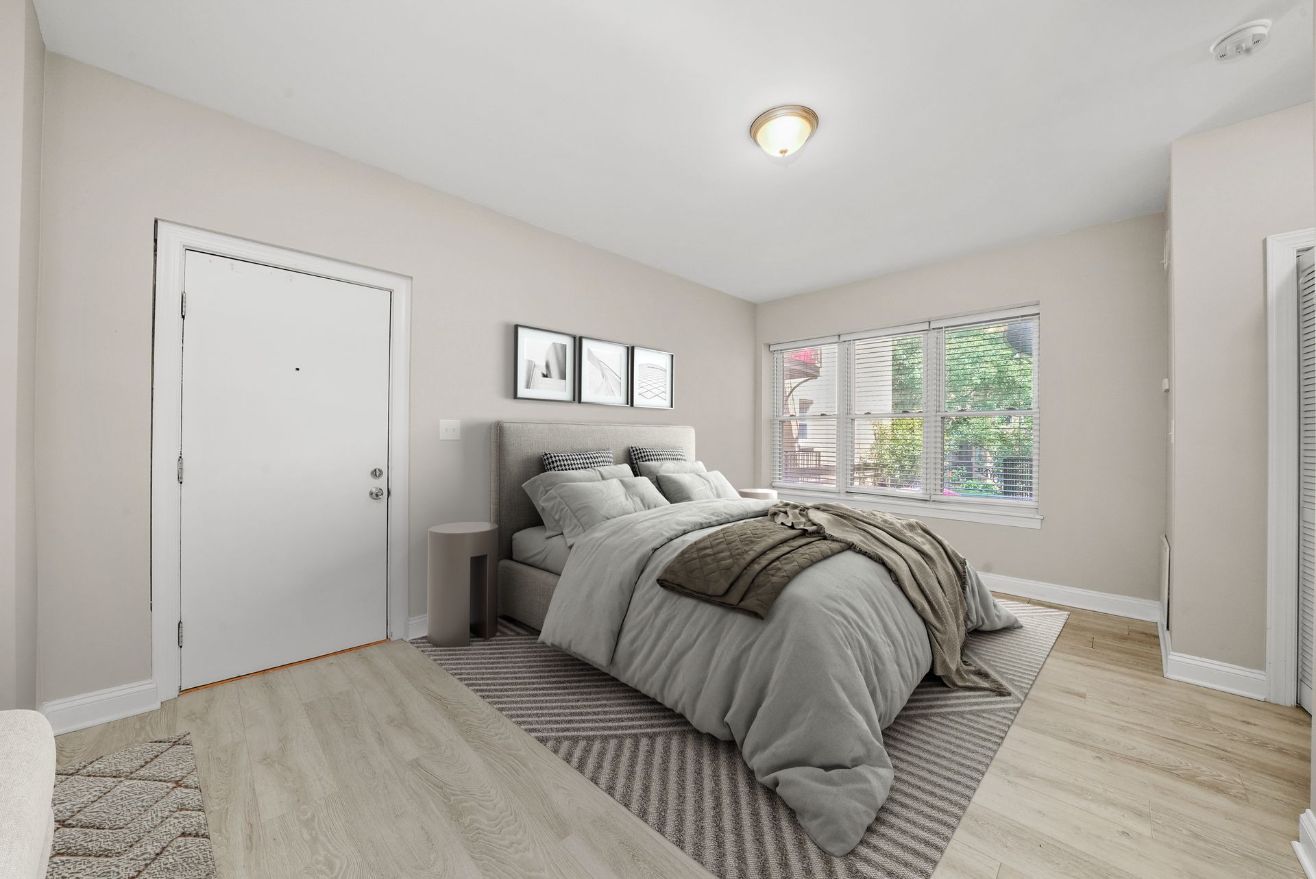 Bedroom with bed, nightstand, window, and artwork; neutral tones.