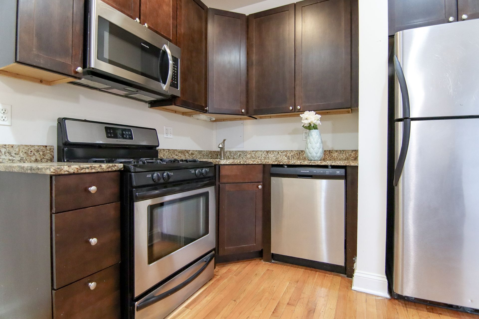 Kitchen with stainless steel appliances, dark wood cabinets, granite countertops, and hardwood floors.