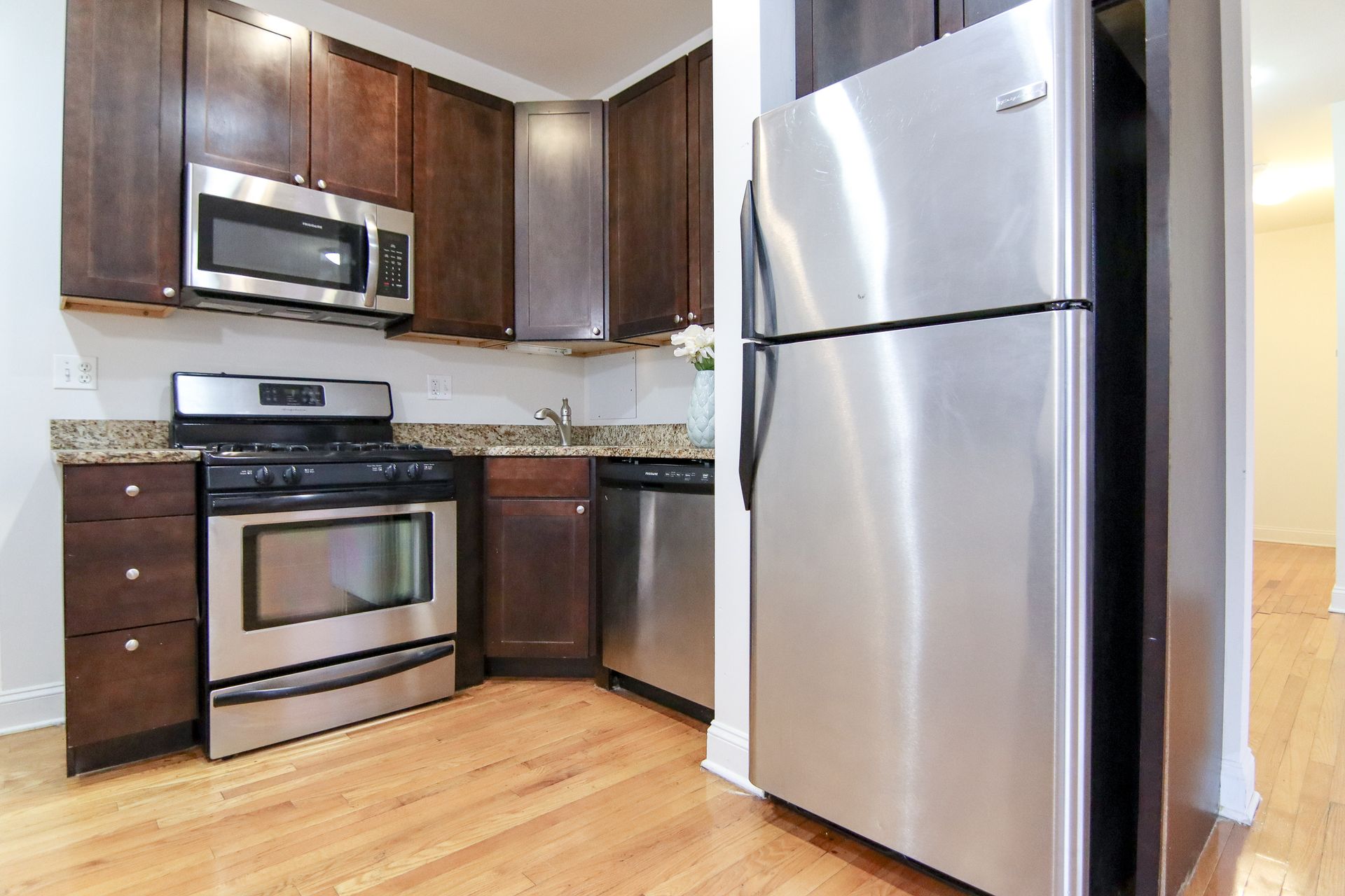 Kitchen with dark wood cabinets, stainless steel appliances, and granite countertops.