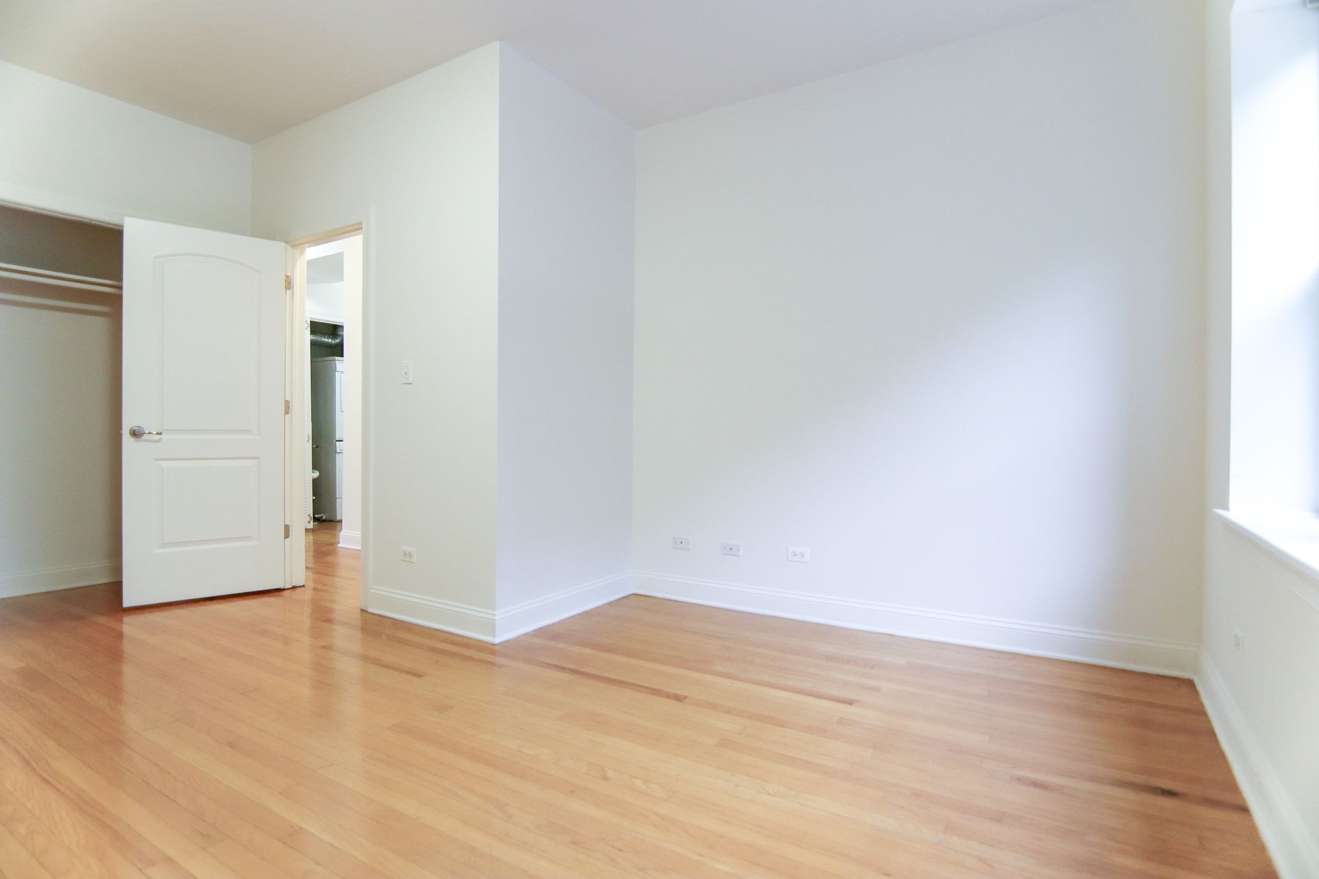 Empty room with wood floors, white walls, and open doors.
