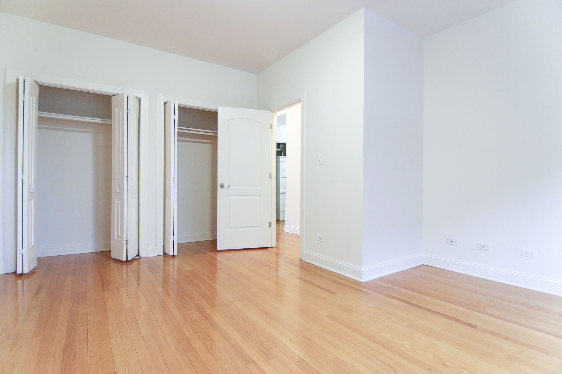 Empty room with hardwood floors, two closets, and open doorway.