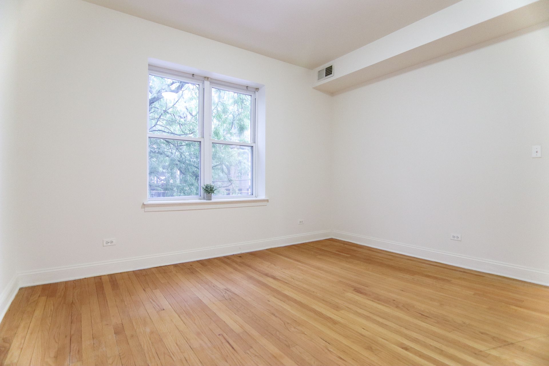 Empty room with hardwood floors, white walls, a window, and overhead beam.