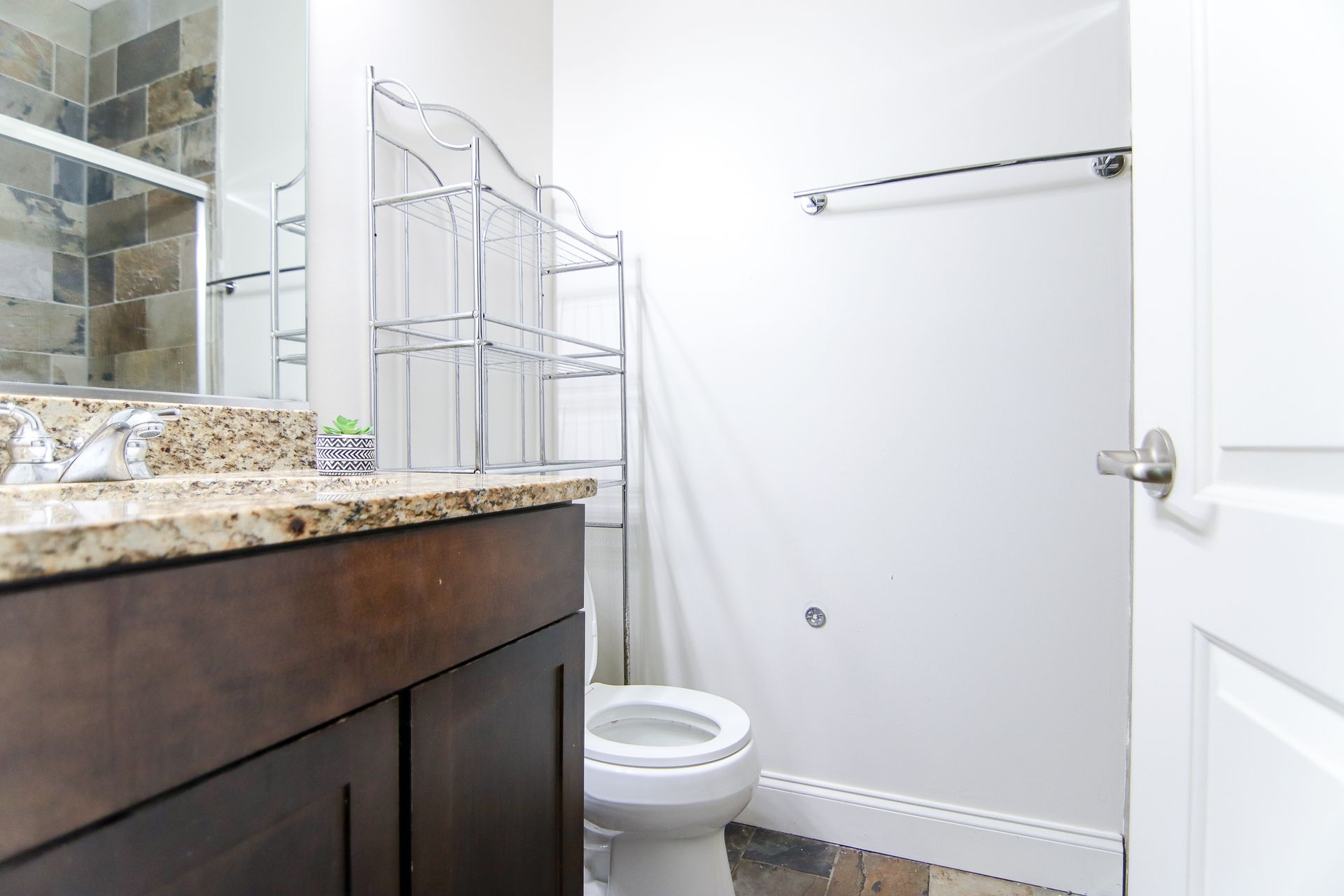 Bathroom interior: vanity, toilet, and shower with stone tiles.