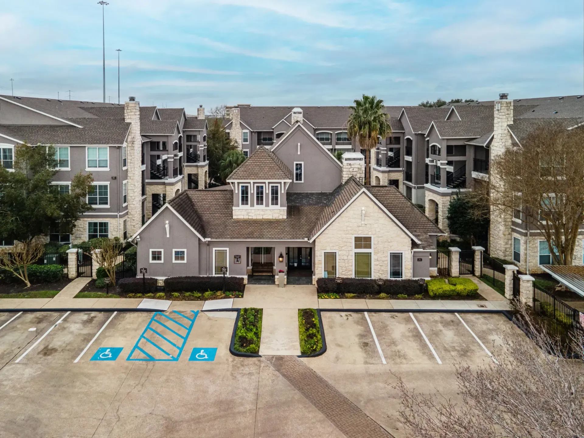 Westpark Ranch Apartments in Houston, TX, exterior with parking spaces; the focal point is a central building with a turret and light-colored stone facade.