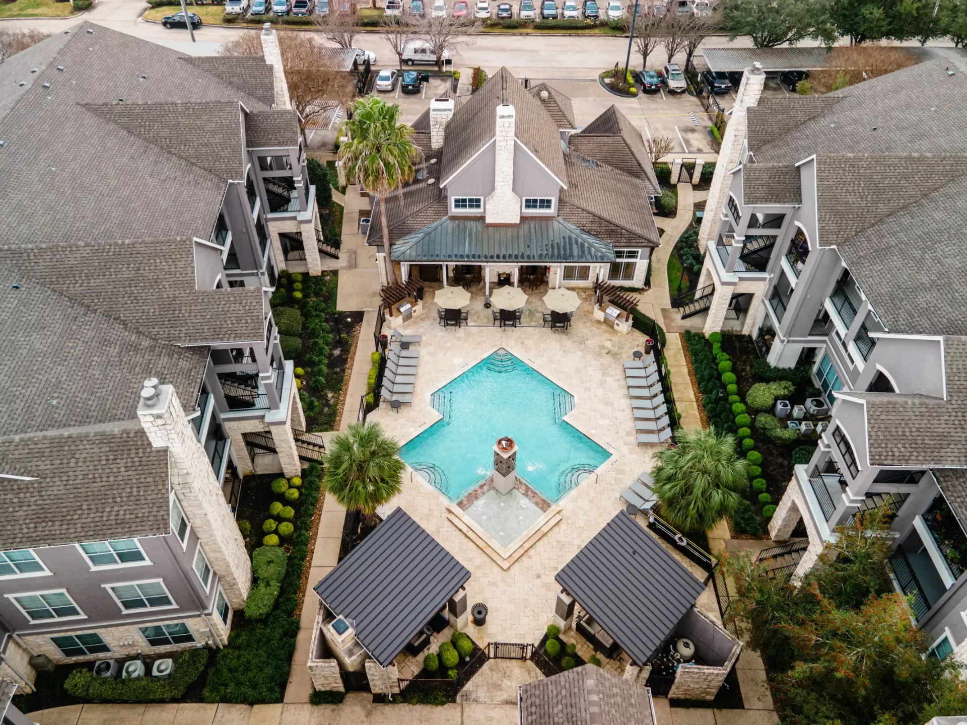 Aerial view of Westpark Ranch Apartments in Houston, TX, with a pool, central clubhouse, and surrounding buildings.