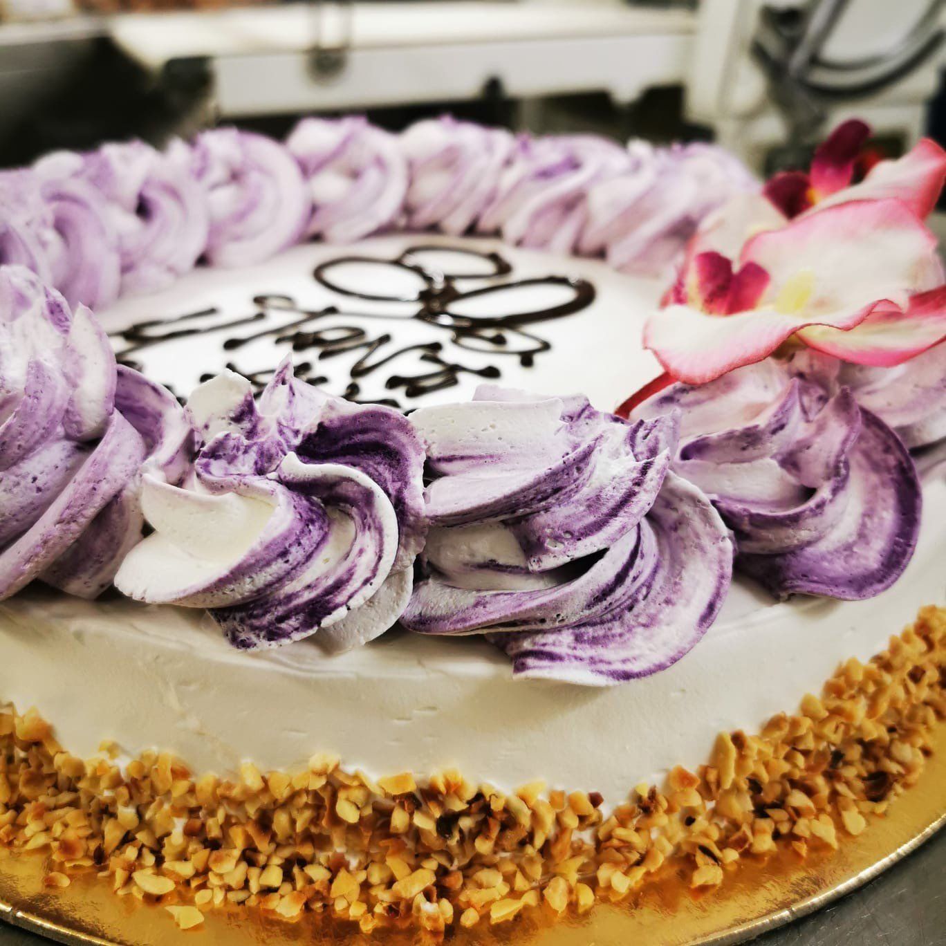 Torta decorata con glassa viola e bianca, noci e un fiore.