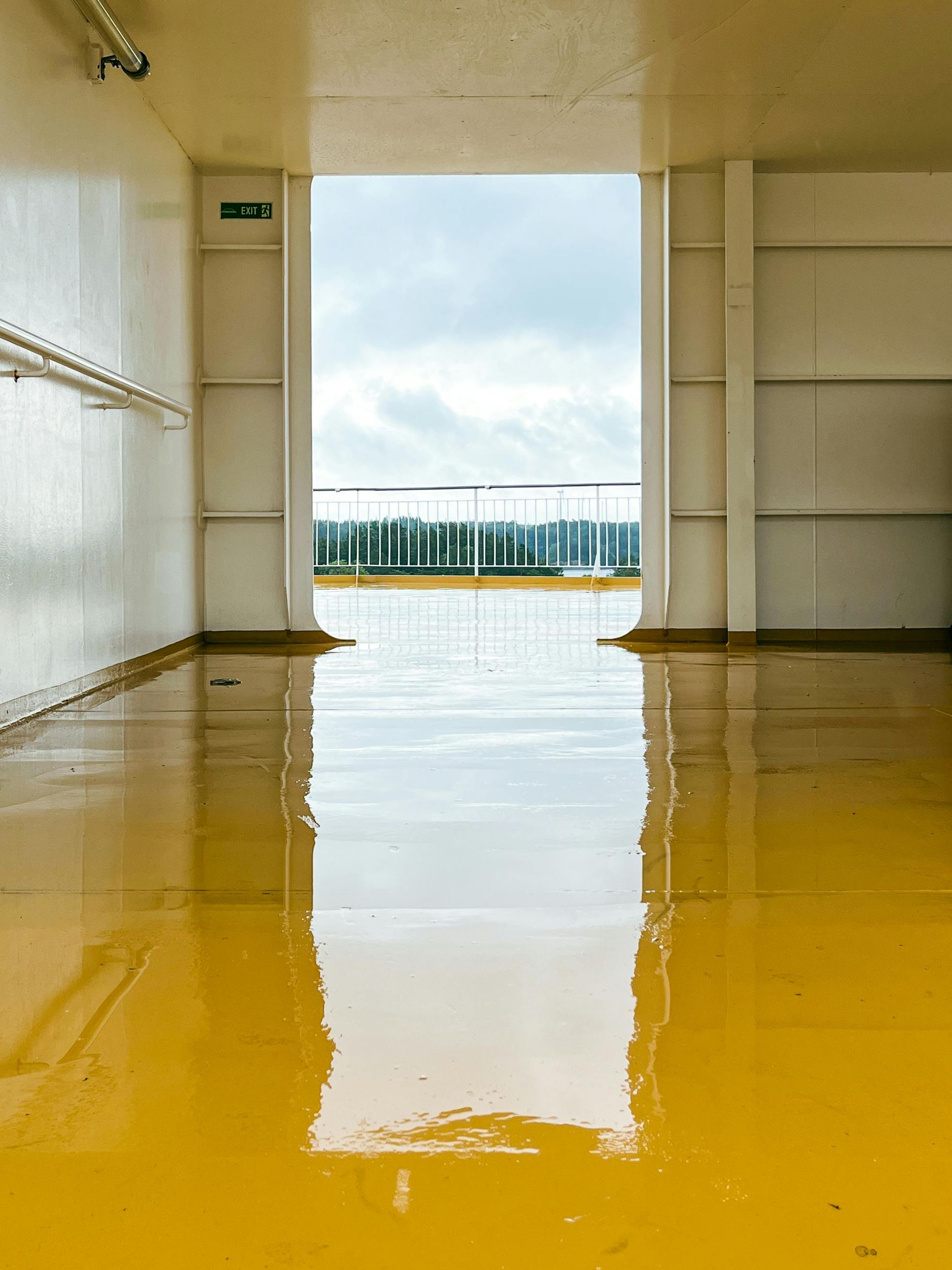 Flooded indoor corridor with yellow water reflecting a doorway and distant windows