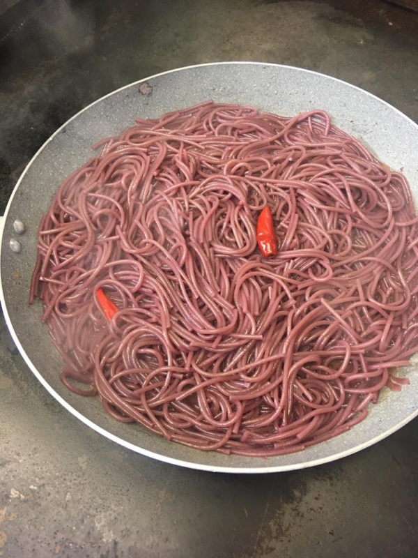 Esterno di un piccolo bar con panche bianche. Rivestimento grigio, finiture marroni e ampie finestre riflettono l'esterno.