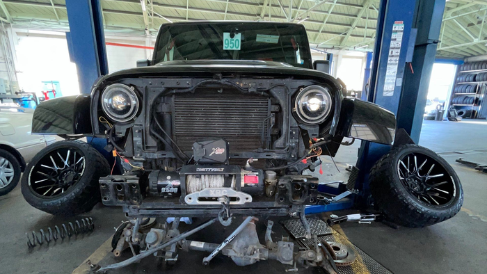 Black Jeep Wrangler in a repair shop with front end disassembled for repairs | Angel's Auto Repair And Service